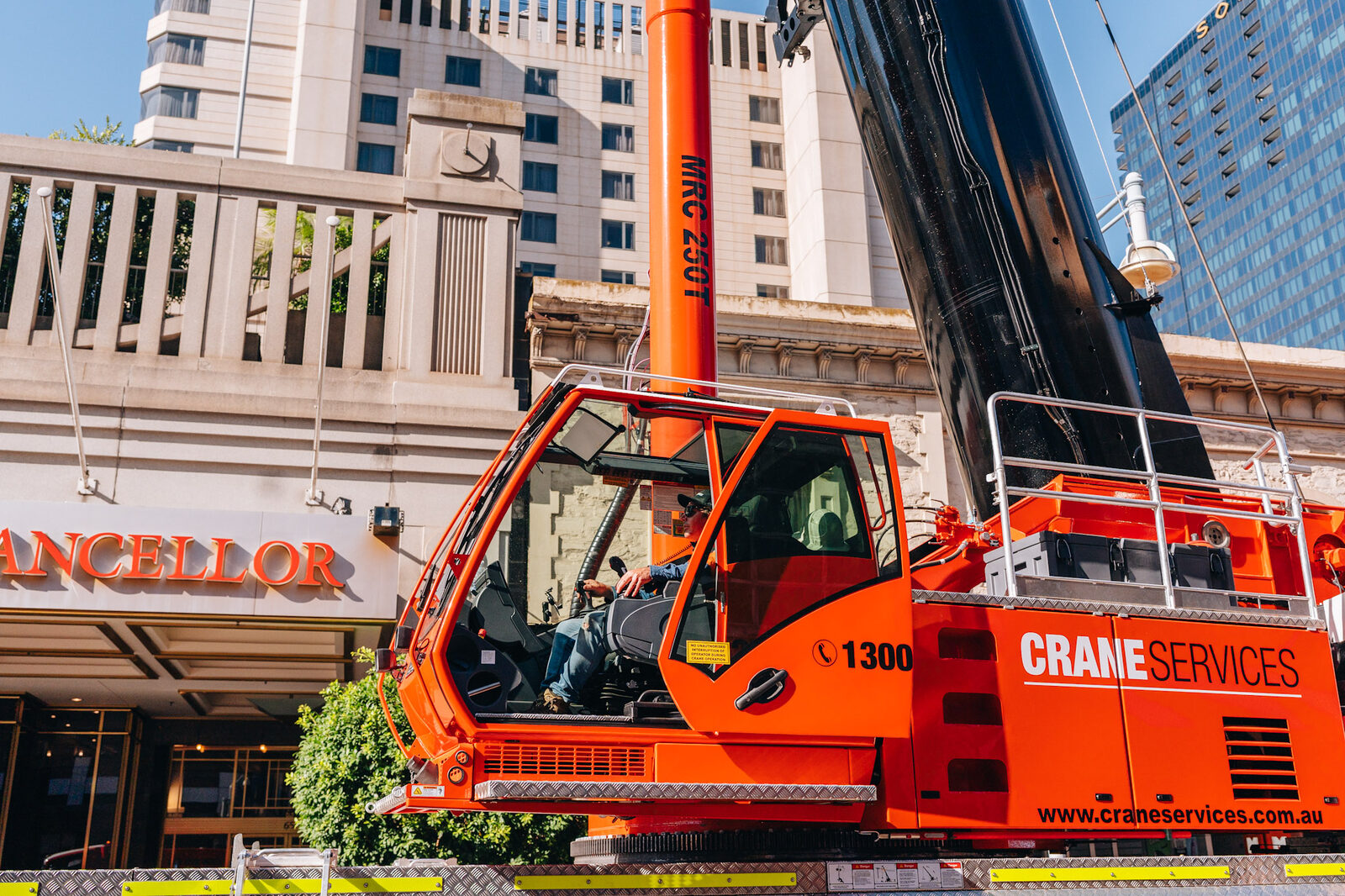 The lattice boom of a mobile crane against a clear blue sky, shot from below.